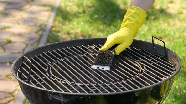 Gloved hand cleaning charcoal grill grate