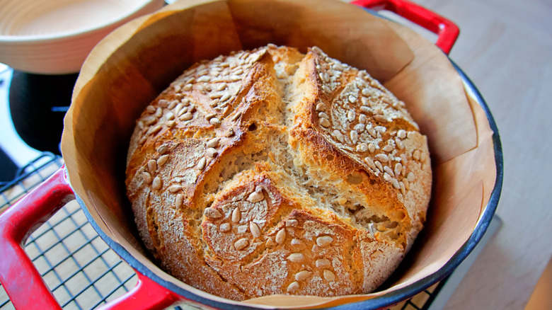 Red Dutch oven with a sourdough loaf of bread inside