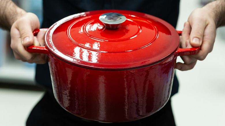Hands holding enameled Dutch oven