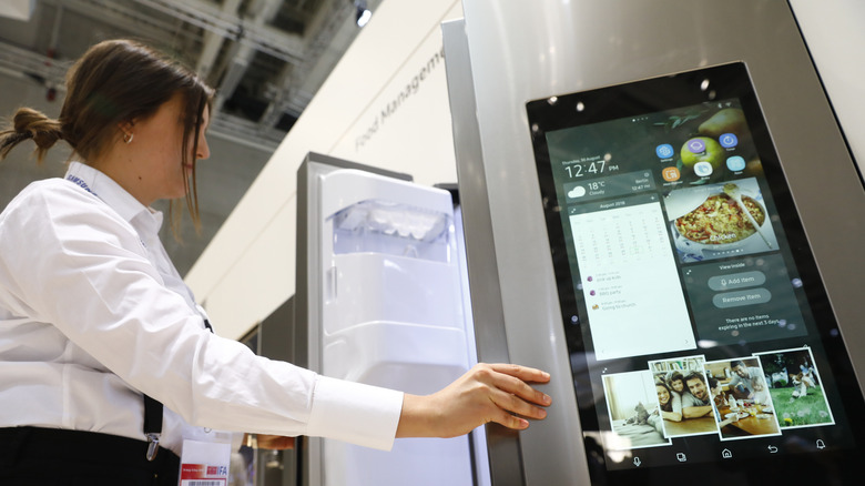 Person looking inside Samsung fridge at electronics convention.
