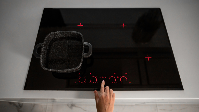 Hand turning on an induction stovetop