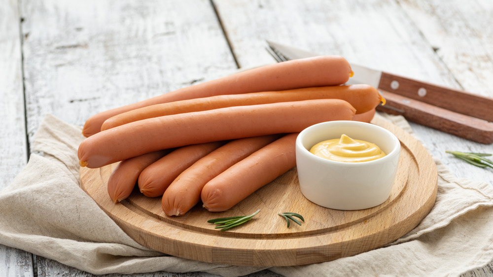 raw hot dogs on cutting board with mustard