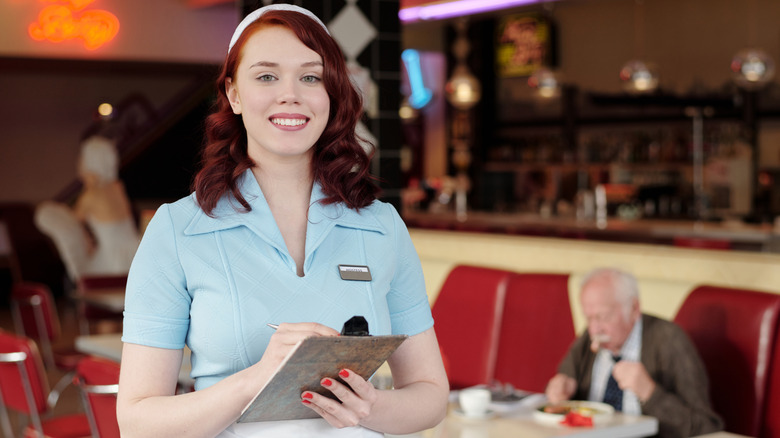 A smiling waitress ready to take your order in a retro diner
