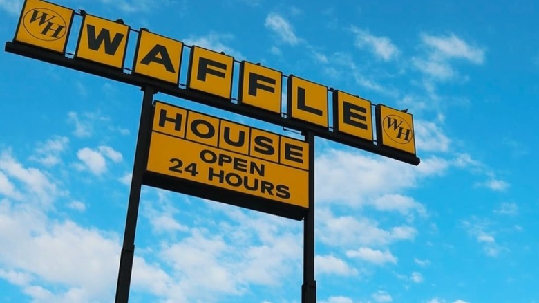 A Waffle House sign advertising 24/7 service against a blue sky