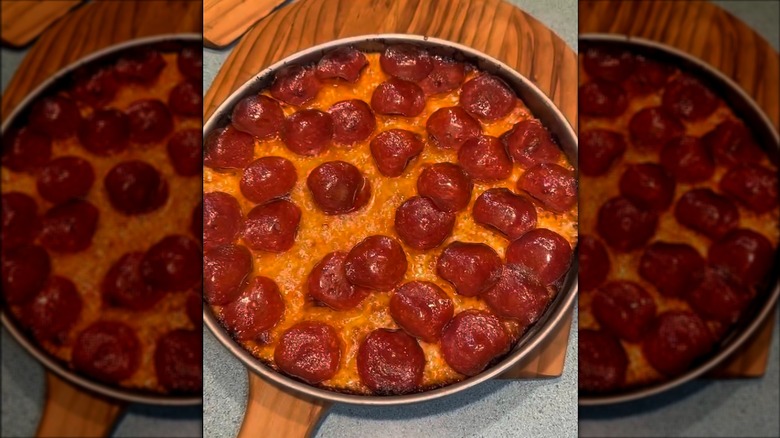 Pepperoni pizza in pan on wooden paddle