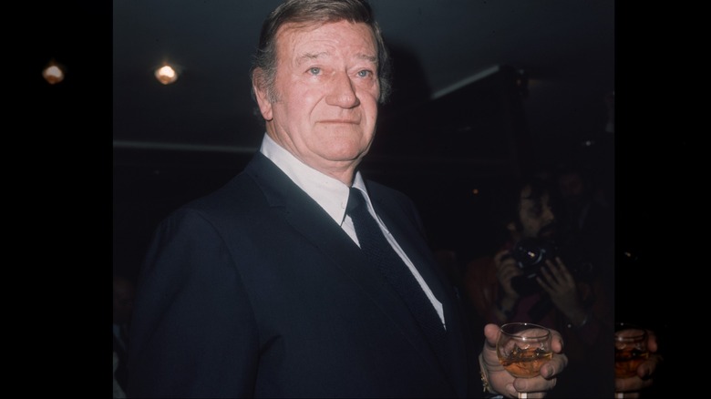 John Wayne holding a bourbon whiskey on the rocks