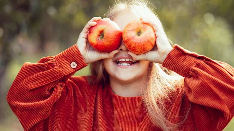 Girl holding apples up as eyes