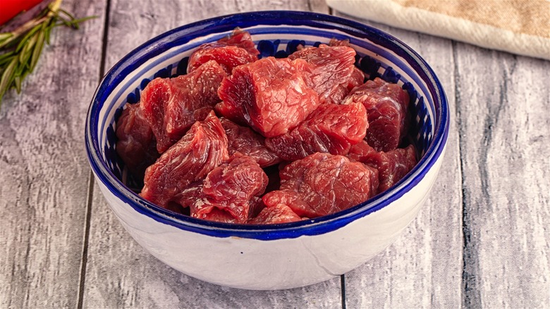 A bowl of raw beef chunks.