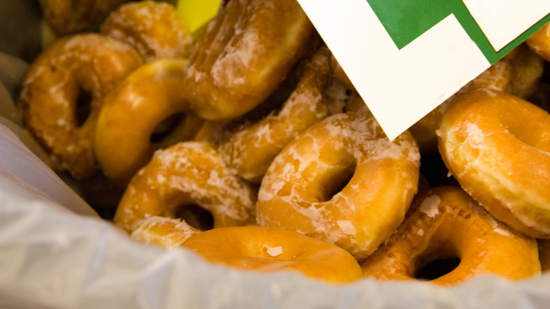 Lined trash can full of glazed doughnuts.