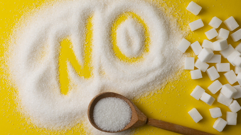 NO written in pile of spilled sugar and sugar cubes on yellow background