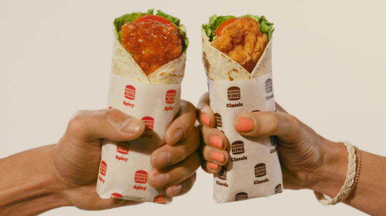 hands holding two royal chicken wraps