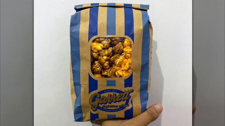 Hand holding up a bag of chicago mix popcorn from Garrrett