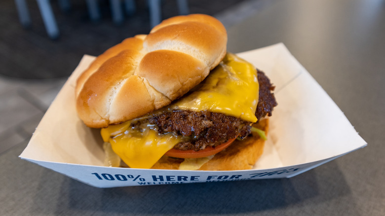 A Culver's ButterBurger sits in a paper boat on a table.