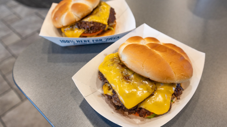 Two Culver's ButterBurgers sit in paper boats on a table.