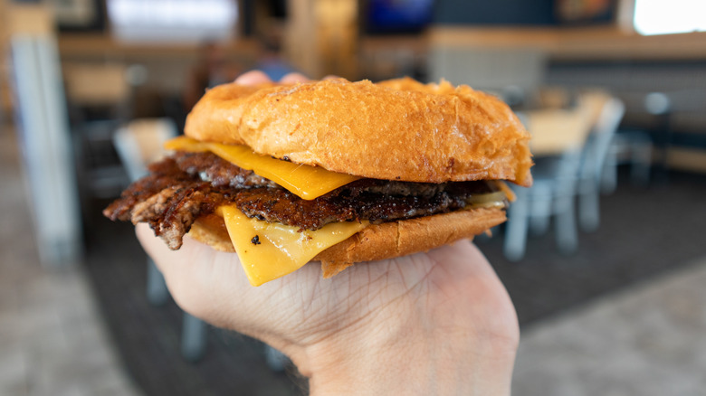 Hand holds a Culver's ButterBurger.