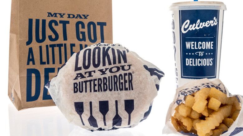 Wrapped Culver's ButterBurger is positioned alongside a soda cup, fries, and a brown bag.