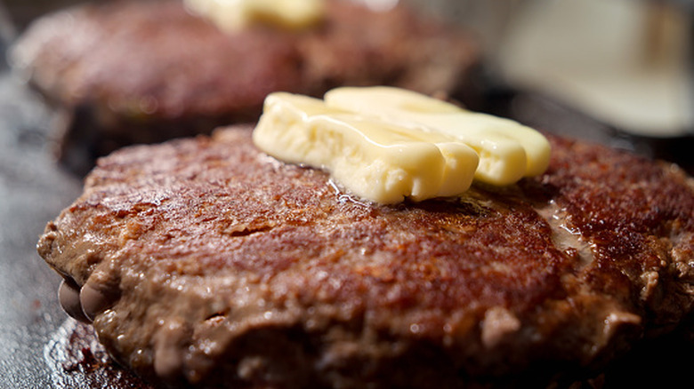 Butter melts atop hot burger patties.