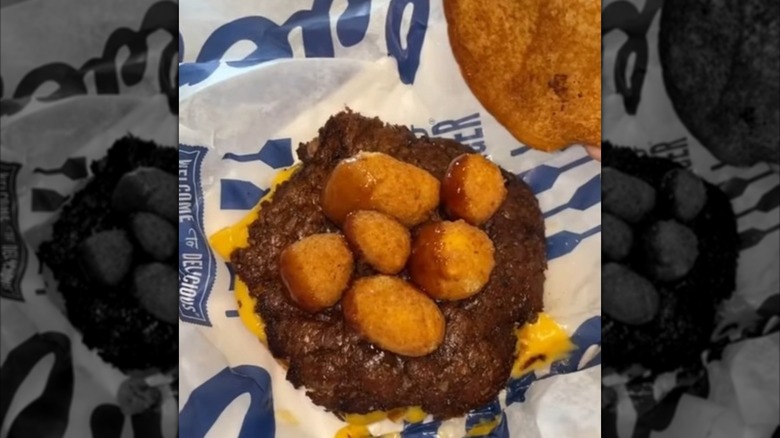 Culver's cheese curds placed on top of the patty of a ButterBurger in Culver's burger wrapper
