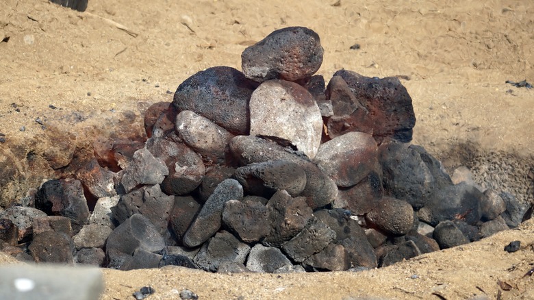 The smoldering pit of volcanic rock that makes up a traditional Hawaiian bbq pit