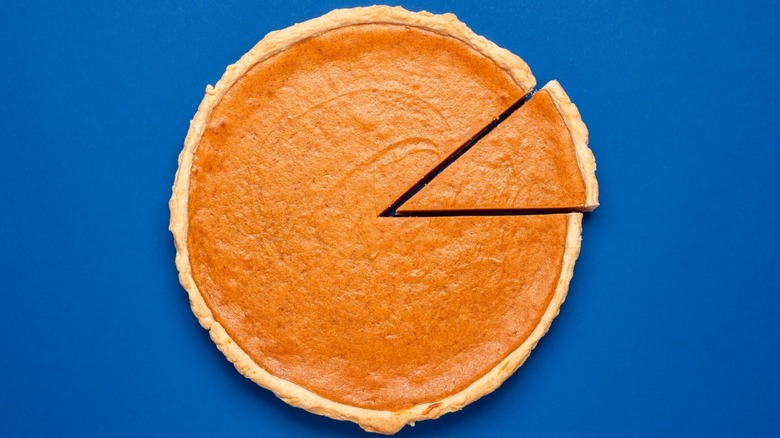 Whole pumpkin pie with slice cut