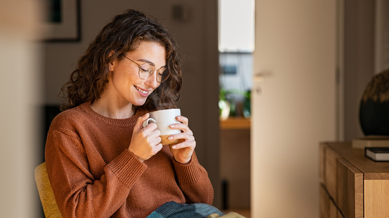 Person holding a white tea cup