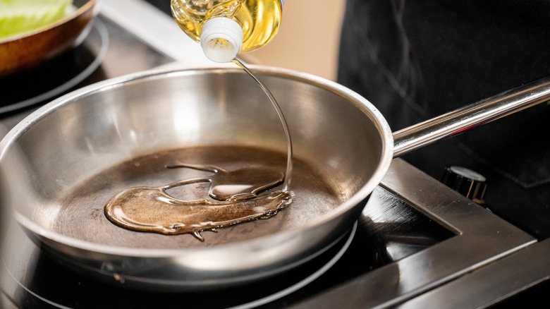 Oil being poured into stainless steel pan