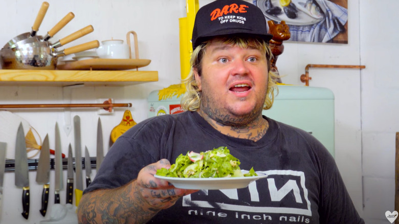 Matty Matheson holding up a plate of green leaf lettuce salad