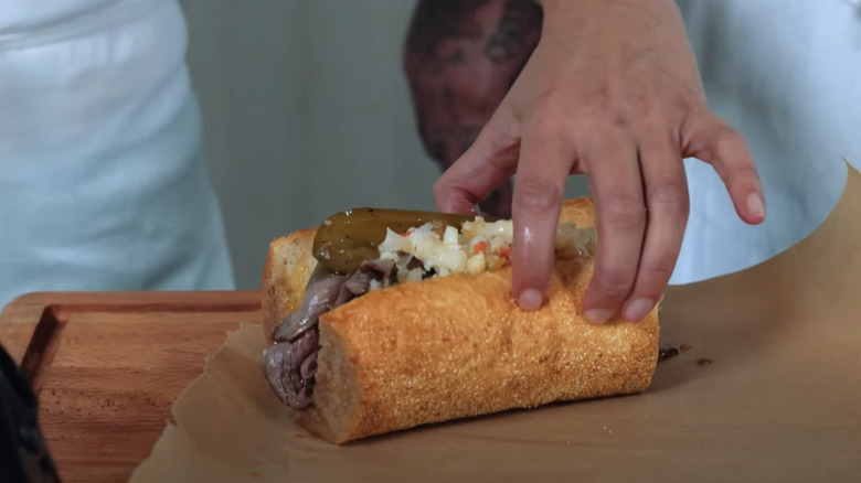 A hand holding an Italian beef sandwich cooked by Matty Matheson