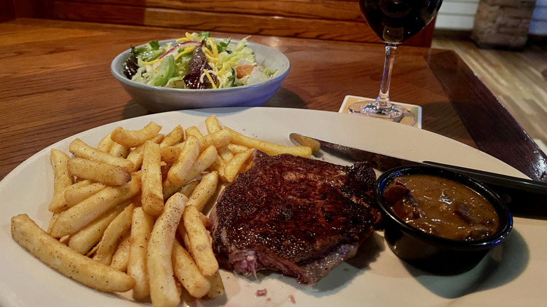 Steak, fries, and salad at a booth in Outback Steakhouse