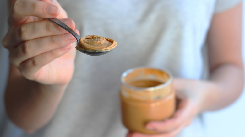 Person holding spoonful of peanut butter