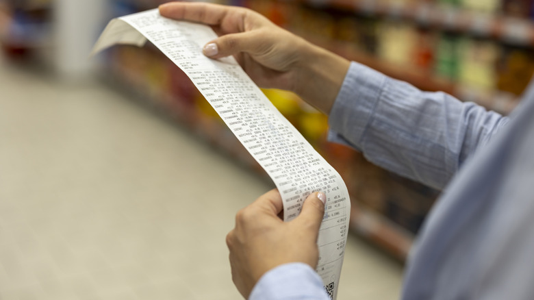 A person holding a long receipt
