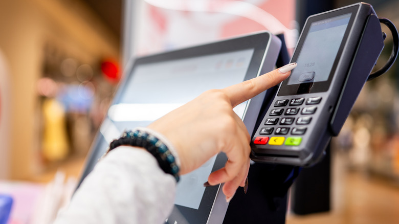 A woman completing a self-checkout transaction