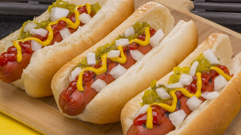 Three hot dogs with toppings 