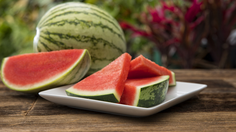 Sliced watermelon on a plate in front of a whole watermelon