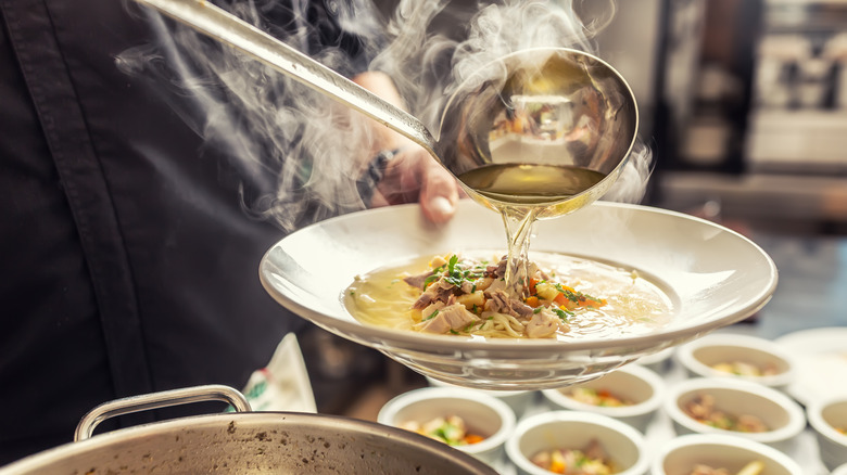 Soup being ladled into a bowl 
