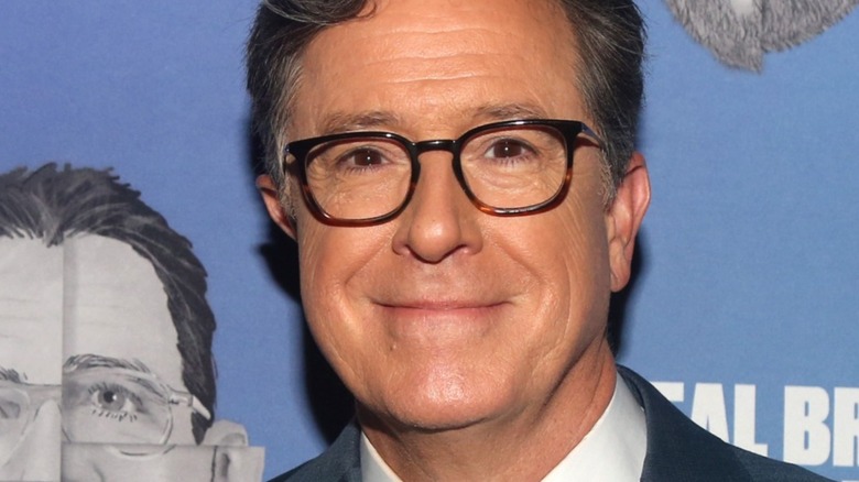 Stephen Colbert smiling in glasses