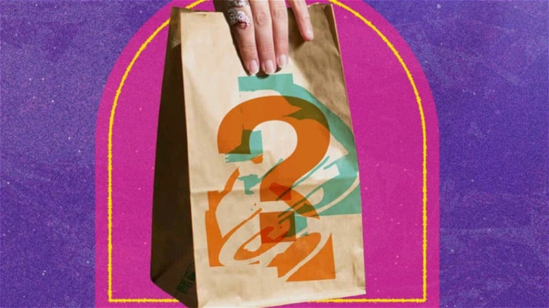 person holding taco bell bag printed with question mark