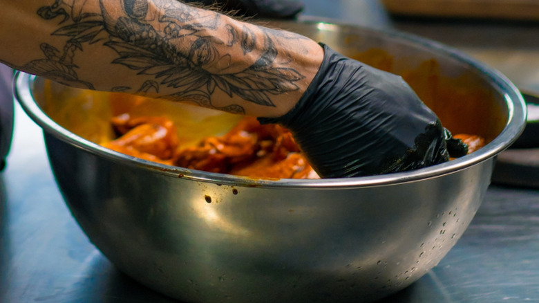 saucing hot wings in bowl