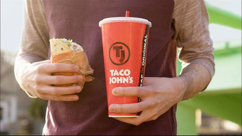 Man holding taco and cup