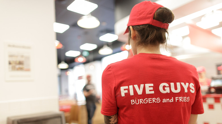 Five Guys employee wearing uniform shirt and hat