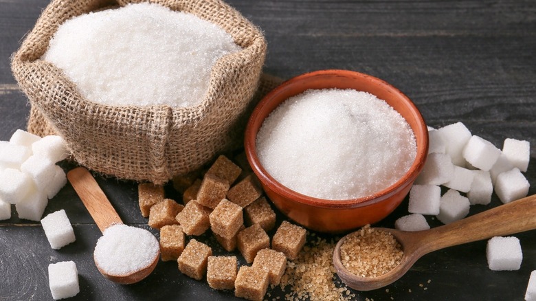 Bags of white sugar next to cubes and spoons
