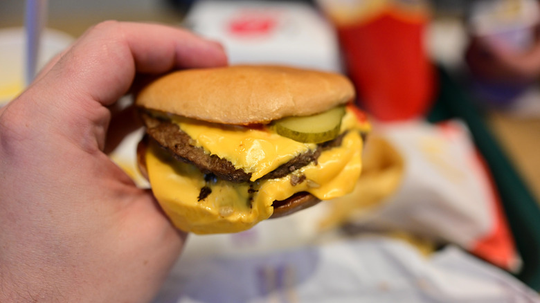 Hand holding a McDonald's double cheeseburger