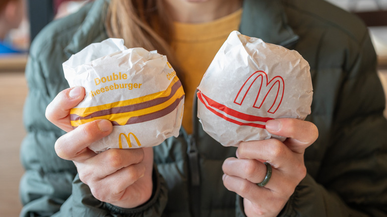 Person holding two wrapped burgers from McDonald's