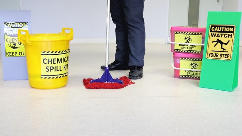 Person mopping chemical spill with yellow bucket