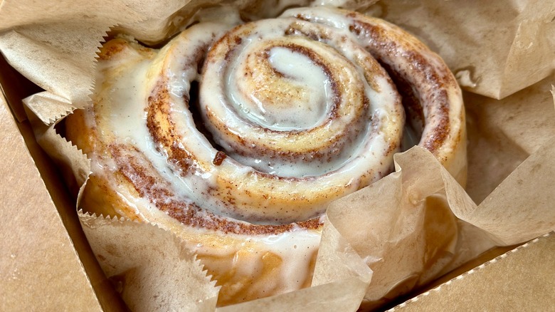 Close-up of cinnamon roll in brown paper.