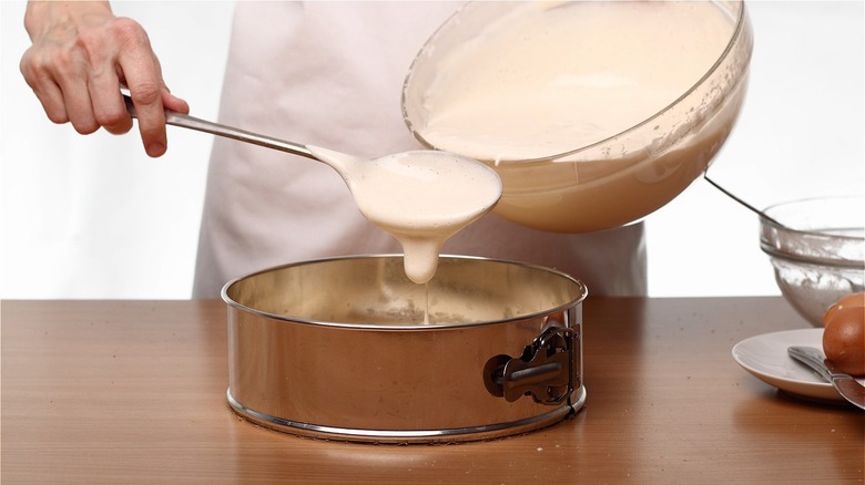 Person holding cake in a springform pan with oven mitts