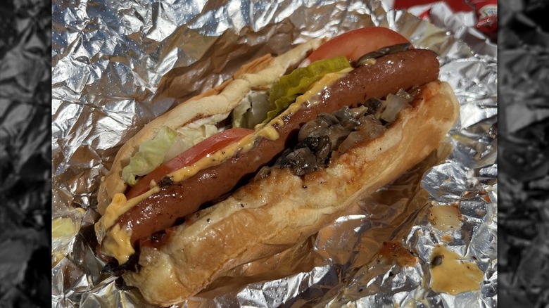 A Five Guys bacon and cheese hotdog sandwich on foil