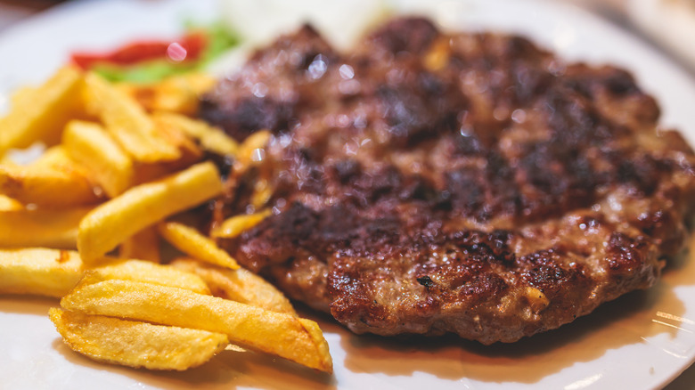 A hamburger patty with a side of fries