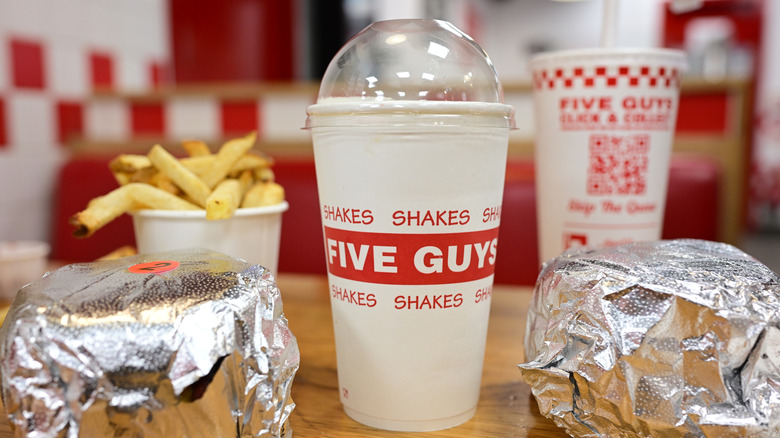 Five Guys french fries, two drinks, and two wrapped burgers