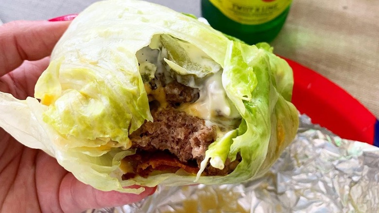 A hand holding a Five Guys lettuce wrap that's been bitten into